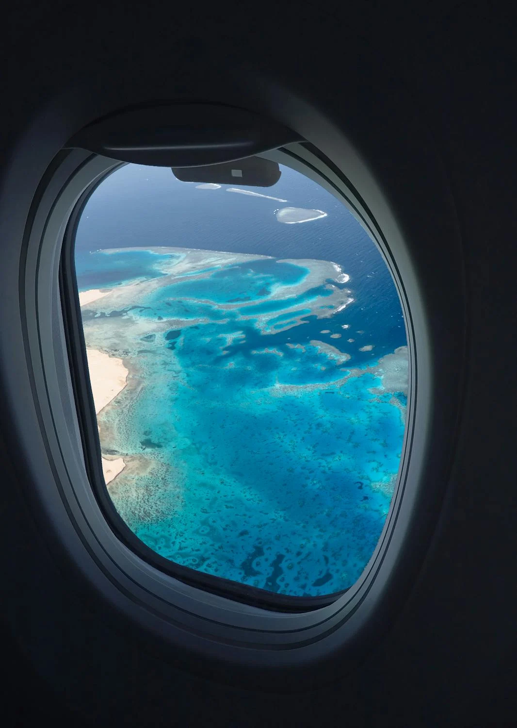 A tropical ocean and beach shore view from a Airplane window