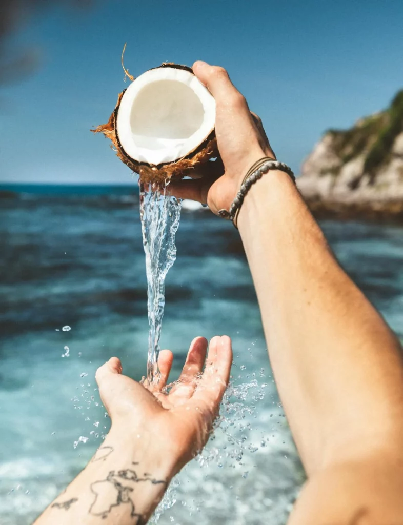 Person Pouring Coconut Water on Their Hand and Their Arm having a World Tattoo