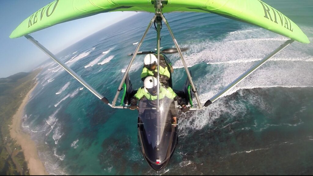 A green aircraft flying above Hawaii's ocean shore