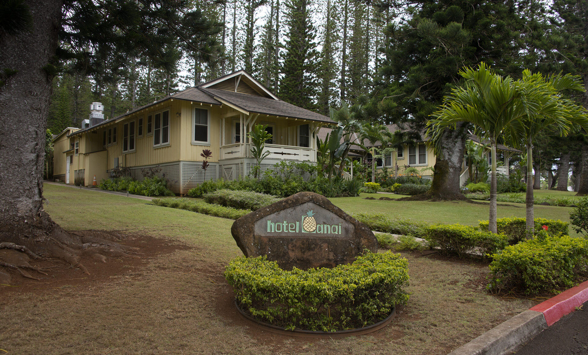 A sign upfront saying Hotel Lanai where a boutique hotel with a rustic modern style behind it. Located in the heart of Lanai City.