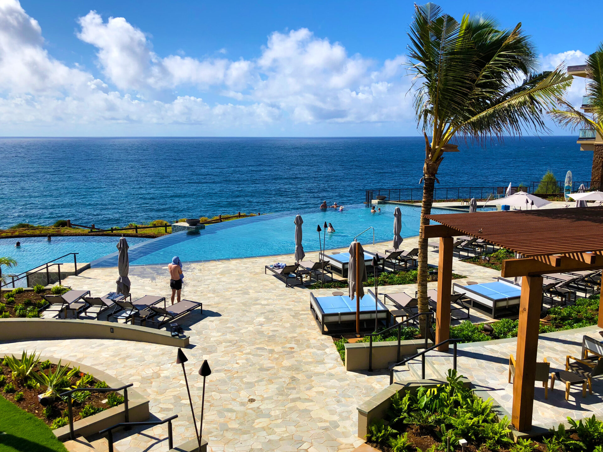 Timbers Kaua‘i Ocean Club & Residences view of people on the beach with wind blowing the palm trees