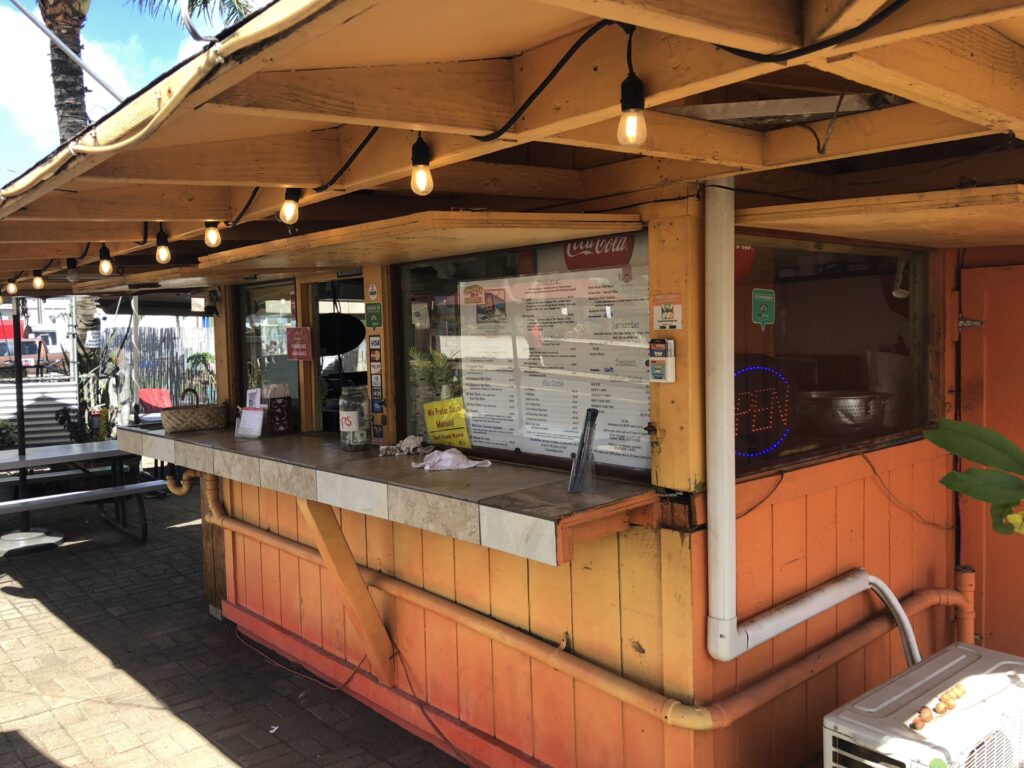 A wooden shack that has a menu on the window called Chicken in a Barrel in Kaua‘i Hawaii