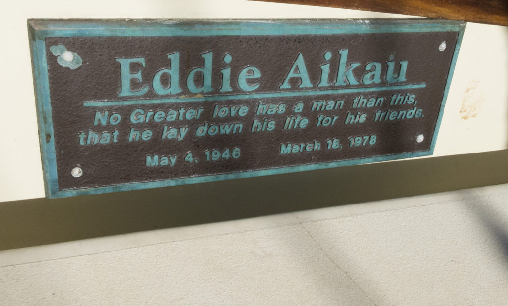 A small teal HDU 3D sign stating Eddie Aikau: No Greater love has a man than this, than he lay down his life for his friends, May 4 1946 - March 18 1978