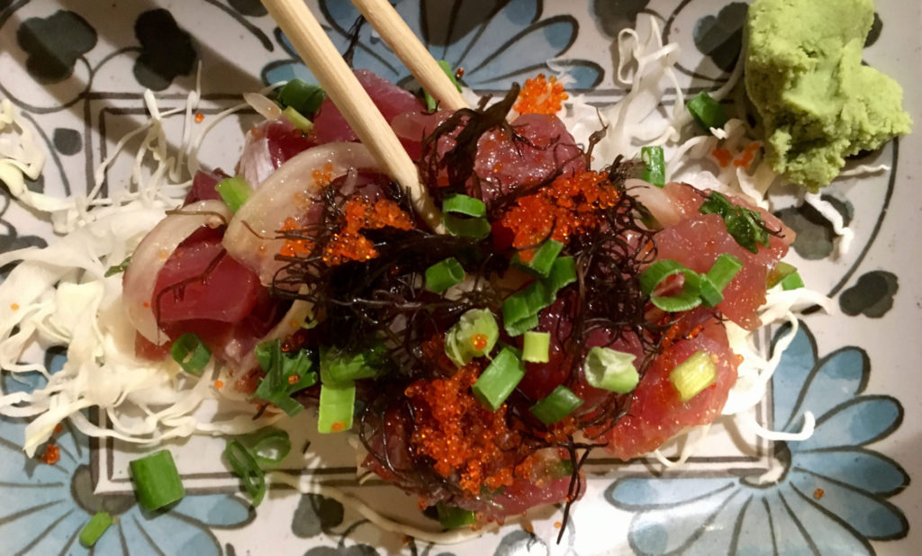 A close up of chopsticks digging in Seared Ahi Poke in a floral design plate made in Kintaro Japanese Restaurant located in Kaua‘i, Hawaii