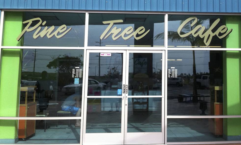 Glass doors with a golden acrylic sign saying Pine Tree Cafe, located in Big Island, Hawaii