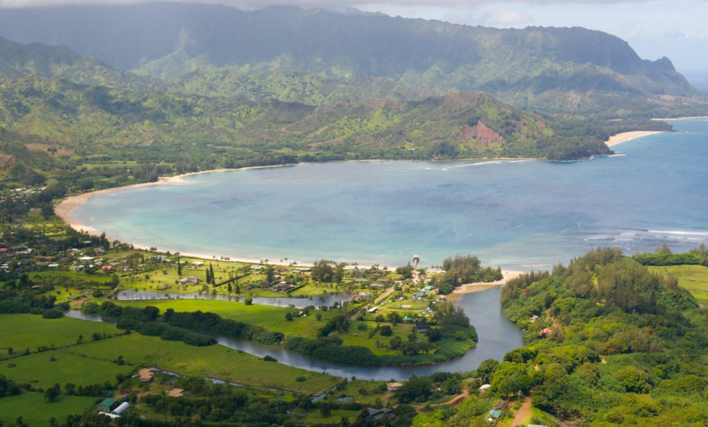 Hanalei Bay is a crescent-shaped beach with verdant mountains in the background, with the waters of the Pacific Ocean against its golden shores, a tropical paradise on the north shore of Kauai, Hawaii.