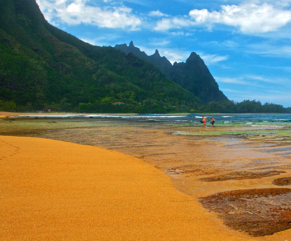 Tunnels Beach full of golden sands, clear turquoise waters, and offshore coral formations on the north shore of Kauai, Hawaii.