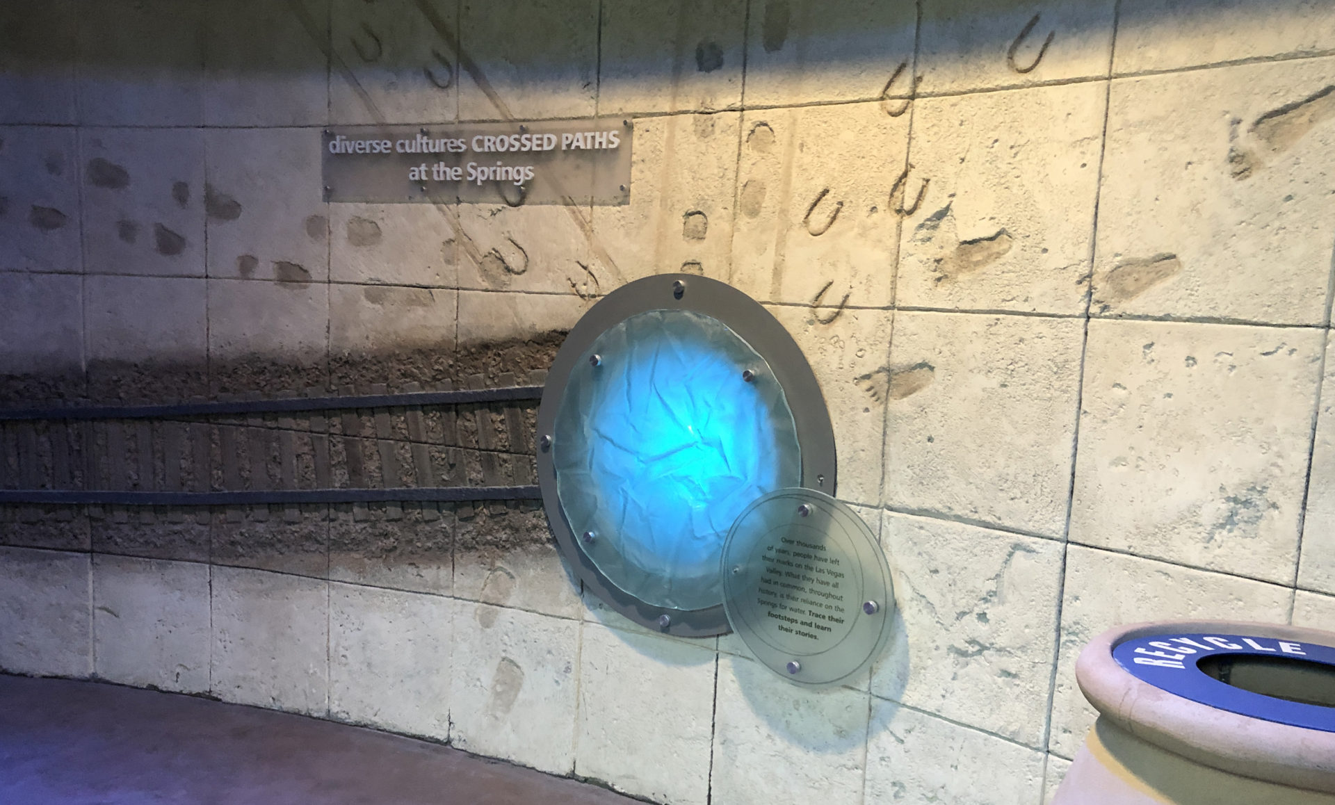 The Origen Museum showcasing a contemporary design of a glowing blue circle with a metal border with signs saying Diverse Cultures CROSSED PATHS at the Springs, the museum that explore the rich cultural and natural history of the Las Vegas region.
