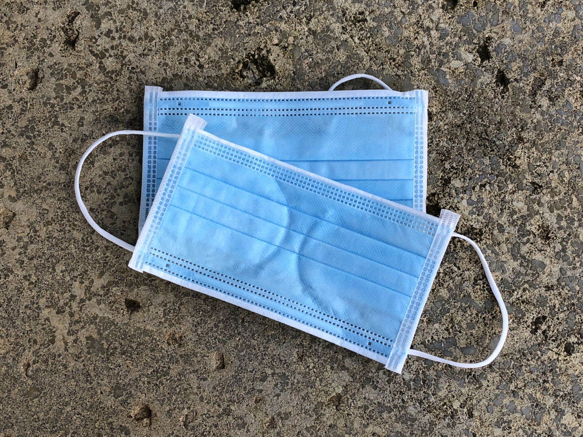 2 Blue masks stacked on each other and placed on a concrete background