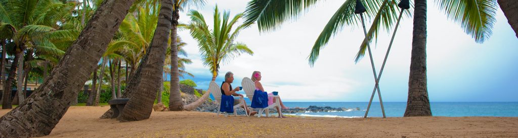 Two People sitting on white chairs on the Inn at Mama’s Fish House's beach view