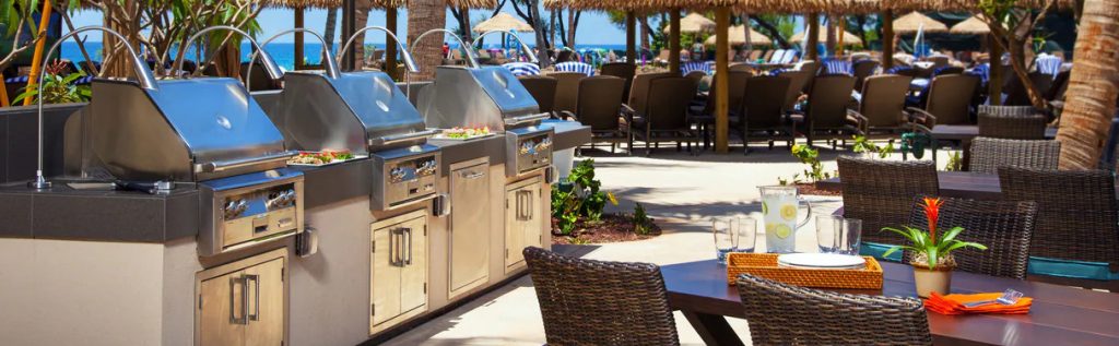 The outdoor area of Westin Nanea Ocean Villas with chairs, tables, umbrellas and grills