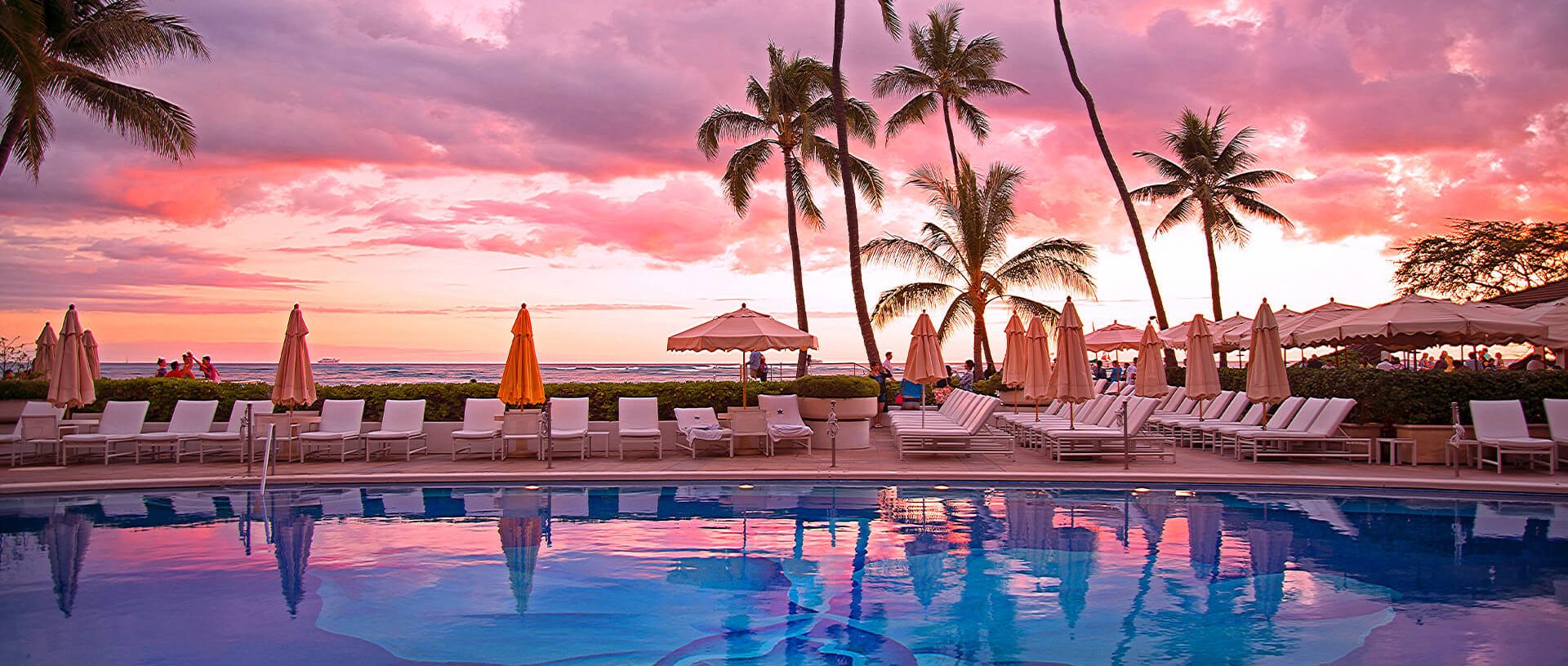 Halekulani poolside with a sunset coloring the sky various pinks and yellows