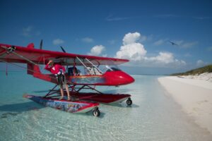 A women standing on the edge of a red plane where it landed on a Bahamas' beach