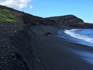 A view of Hawaii's beach shore featuring only black sand